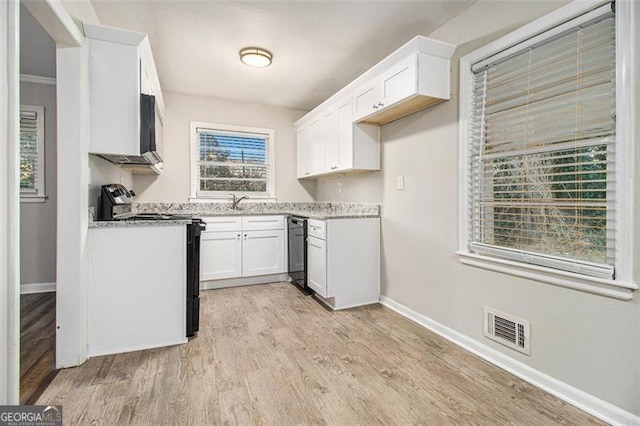 kitchen with white cabinets, black electric range, ornamental molding, light hardwood / wood-style floors, and light stone counters