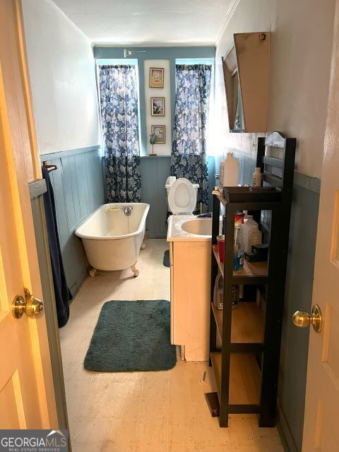 bathroom featuring crown molding, vanity, and a washtub