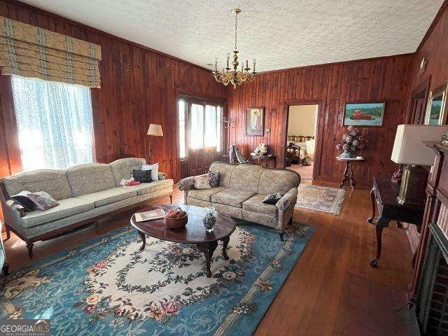 living room featuring dark hardwood / wood-style floors, a healthy amount of sunlight, a textured ceiling, and an inviting chandelier