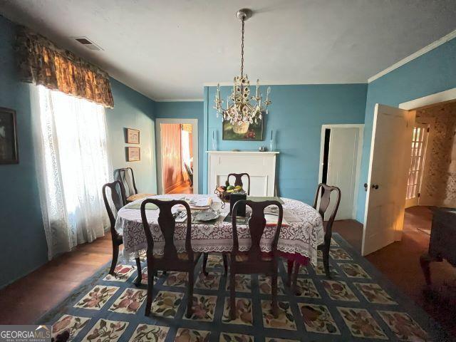 dining room featuring an inviting chandelier, ornamental molding, and dark hardwood / wood-style flooring