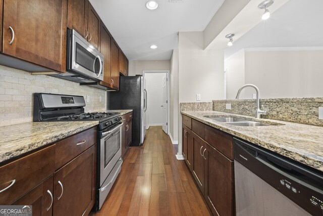 kitchen featuring dark hardwood / wood-style flooring, light stone countertops, sink, and appliances with stainless steel finishes