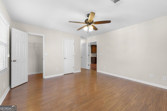 unfurnished bedroom with ceiling fan, dark hardwood / wood-style flooring, and multiple windows