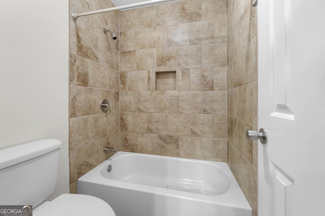 bathroom featuring tiled shower / bath combo and toilet