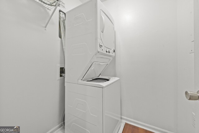 washroom featuring hardwood / wood-style floors and stacked washer and clothes dryer