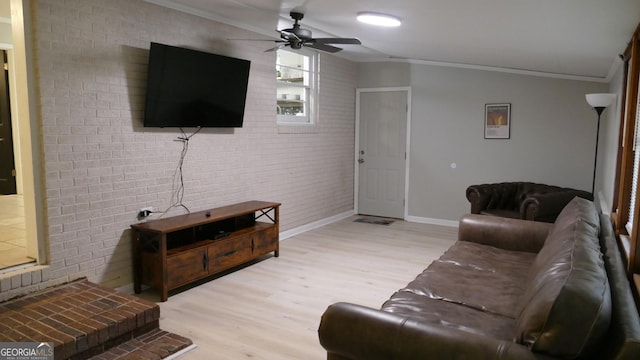 living room featuring ceiling fan, light hardwood / wood-style floors, crown molding, and brick wall