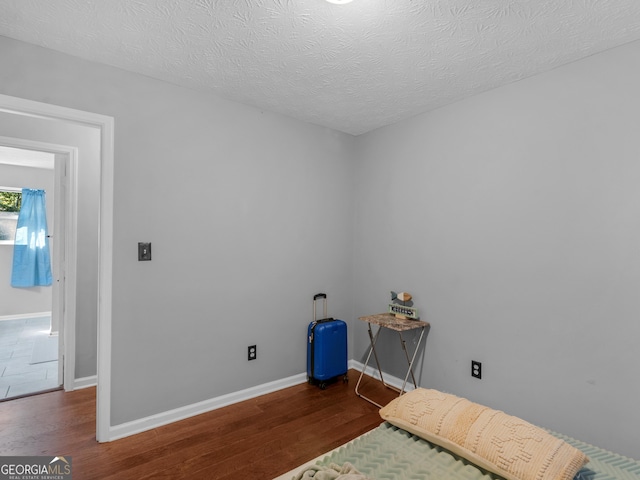 bedroom with a textured ceiling and dark wood-type flooring