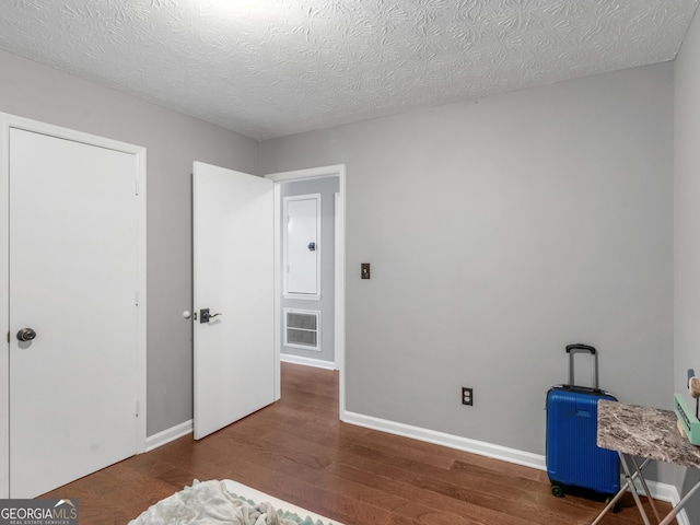 bedroom featuring dark hardwood / wood-style flooring and a textured ceiling