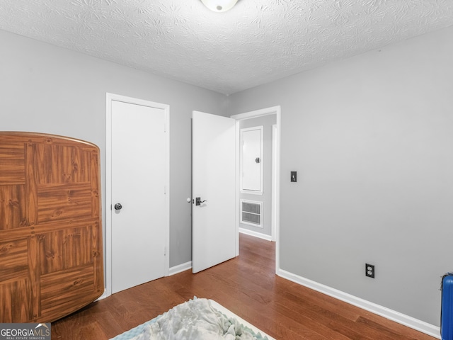 bedroom with a textured ceiling and hardwood / wood-style flooring