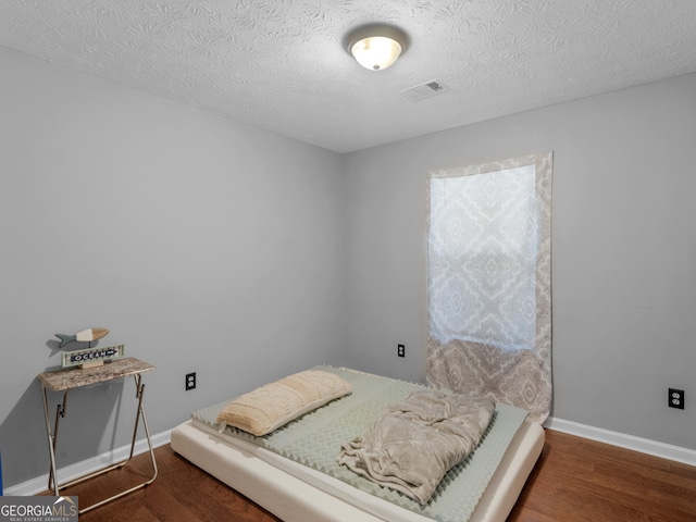 bedroom with dark hardwood / wood-style flooring and a textured ceiling