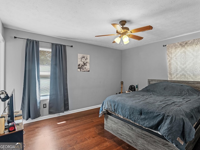 bedroom with a textured ceiling, ceiling fan, and dark wood-type flooring