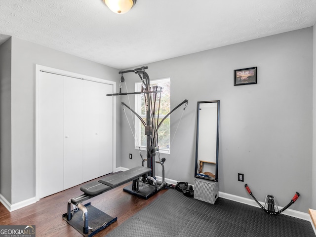 workout area featuring a textured ceiling and dark hardwood / wood-style floors