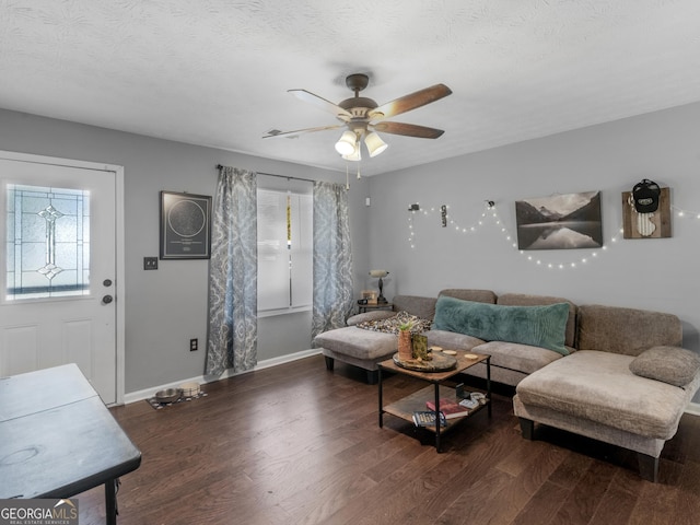 living room with a wealth of natural light, ceiling fan, dark wood-type flooring, and a textured ceiling