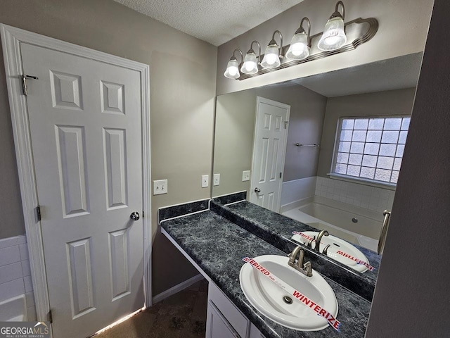 bathroom with a textured ceiling, a bathtub, and vanity