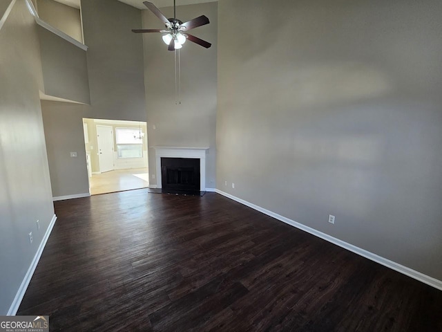 unfurnished living room with ceiling fan, dark hardwood / wood-style flooring, and high vaulted ceiling