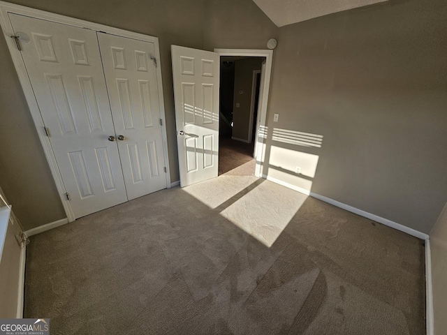 unfurnished bedroom with a closet, vaulted ceiling, and carpet flooring