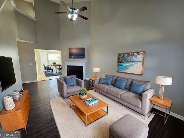 living room with ceiling fan, dark wood-type flooring, and high vaulted ceiling