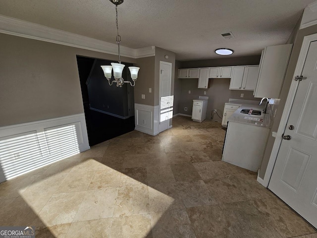 kitchen with a textured ceiling, a chandelier, decorative light fixtures, white cabinets, and sink