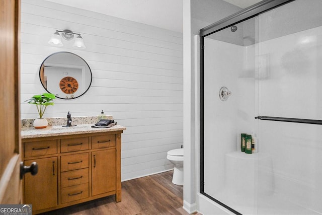 bathroom with hardwood / wood-style floors, vanity, a shower with shower door, and toilet