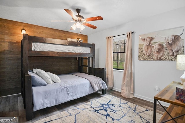 bedroom featuring ceiling fan, dark hardwood / wood-style flooring, and wood walls