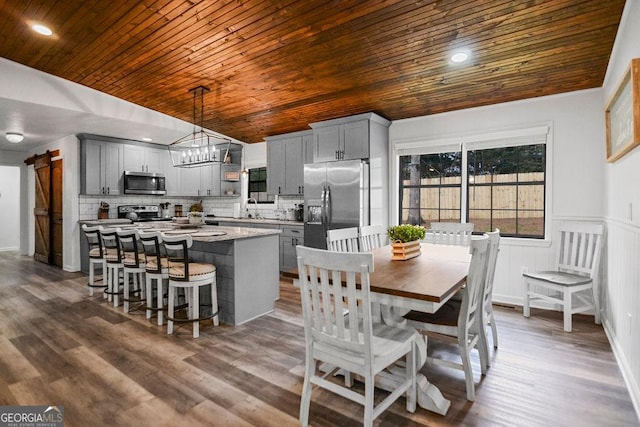 dining area with dark hardwood / wood-style floors, a barn door, and wood ceiling