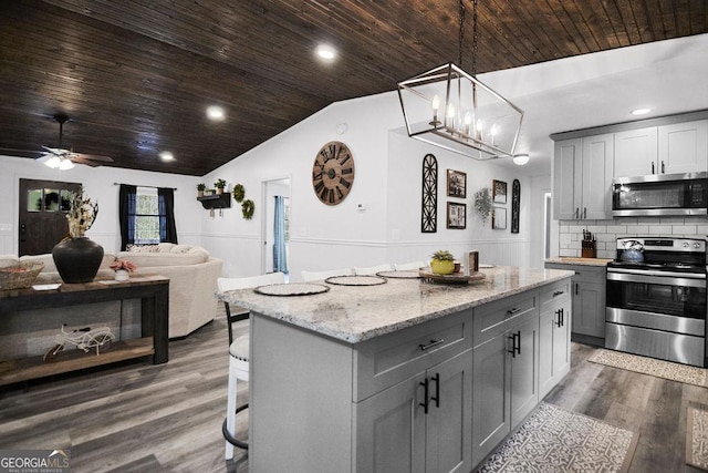 kitchen with decorative backsplash, dark hardwood / wood-style flooring, gray cabinetry, stainless steel appliances, and pendant lighting