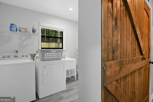 laundry area featuring washing machine and dryer and light hardwood / wood-style flooring