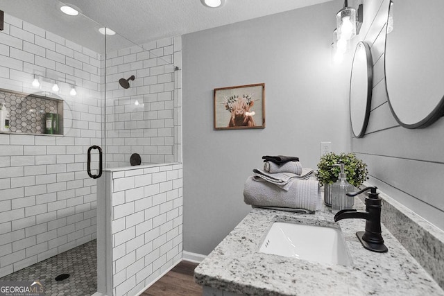 bathroom with hardwood / wood-style floors, vanity, and a shower with shower door