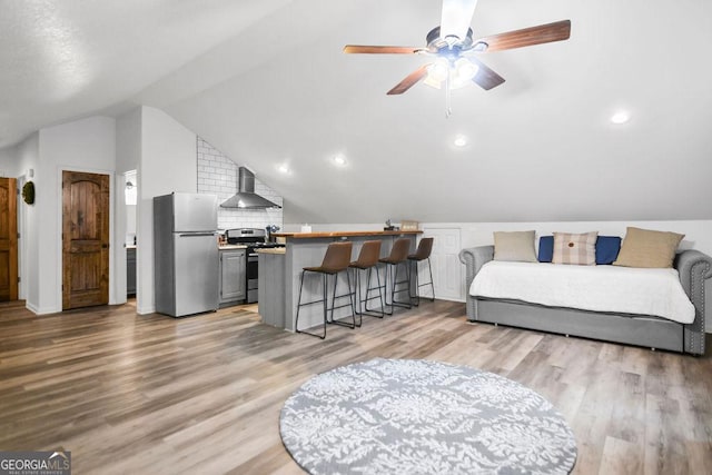 bedroom with ceiling fan, stainless steel fridge, lofted ceiling, and light hardwood / wood-style flooring