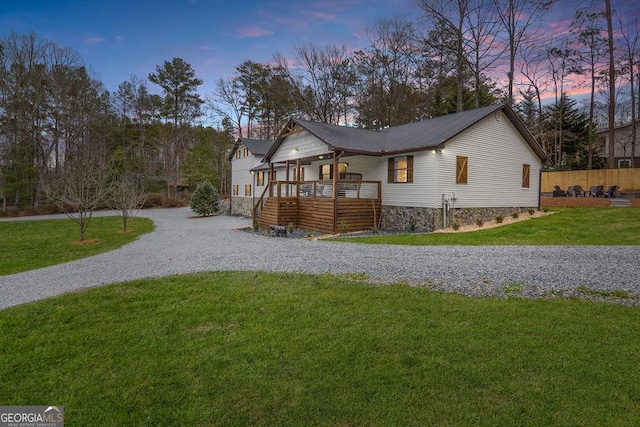 property exterior at dusk with a lawn and a wooden deck