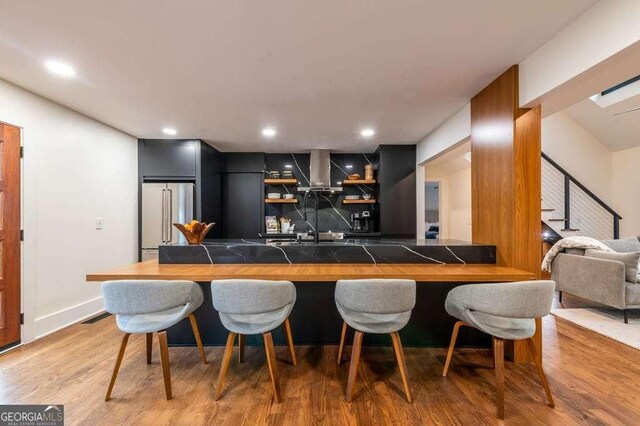 bar featuring tasteful backsplash, high end fridge, and hardwood / wood-style floors