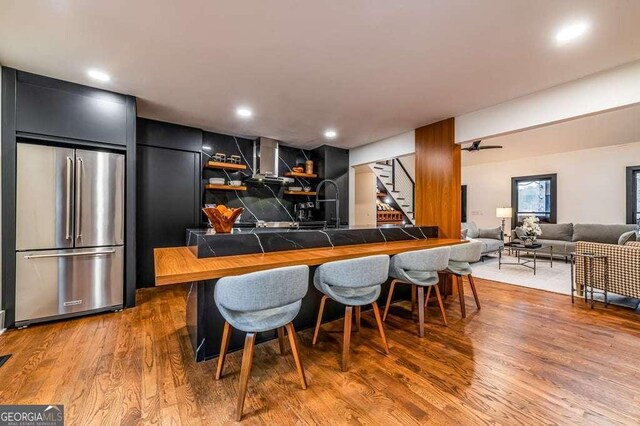 kitchen featuring decorative backsplash, stainless steel appliances, light hardwood / wood-style flooring, and wall chimney range hood