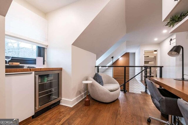 office with beverage cooler, indoor bar, and wood-type flooring