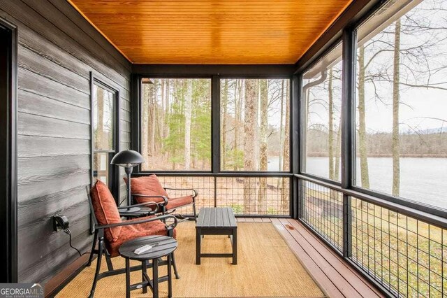 sunroom / solarium featuring a healthy amount of sunlight, a water view, and wood ceiling