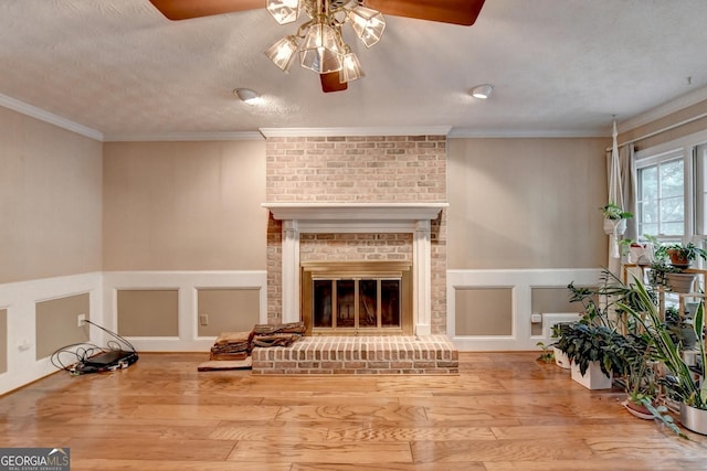 living room featuring a textured ceiling, crown molding, hardwood / wood-style flooring, and a brick fireplace