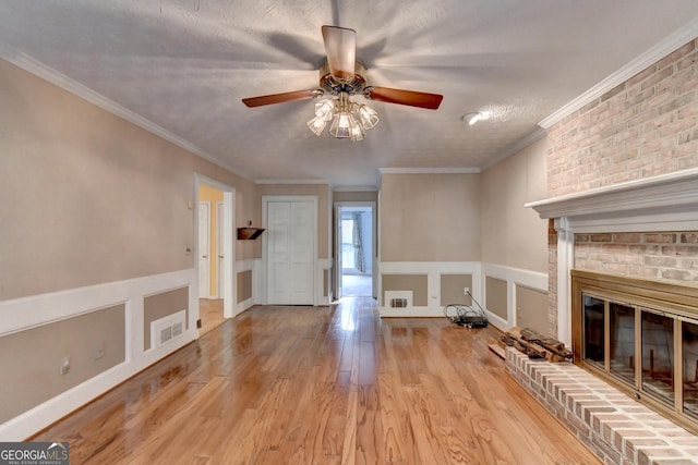 unfurnished living room featuring a fireplace, light hardwood / wood-style flooring, a textured ceiling, and ornamental molding