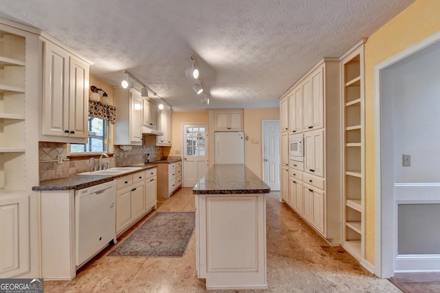 kitchen with a center island, white appliances, rail lighting, sink, and a textured ceiling