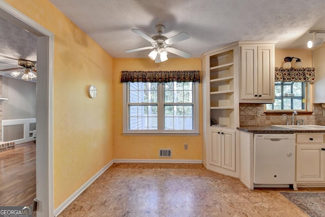 kitchen featuring backsplash, white dishwasher, sink, ceiling fan, and a textured ceiling