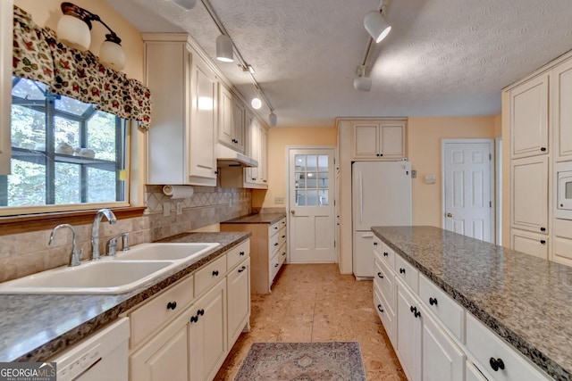 kitchen with rail lighting, tasteful backsplash, white appliances, a textured ceiling, and sink