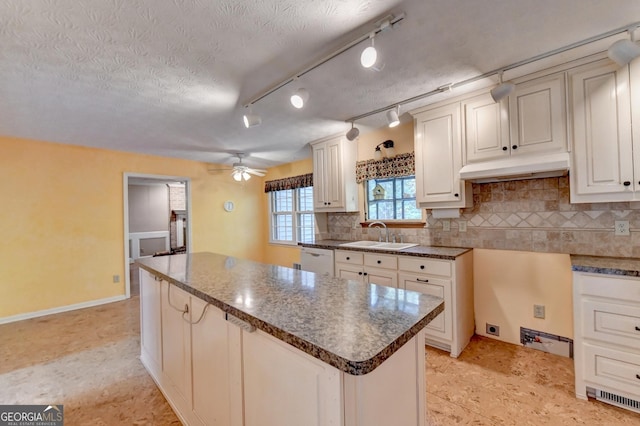 kitchen with ceiling fan, dishwasher, sink, a textured ceiling, and a kitchen island