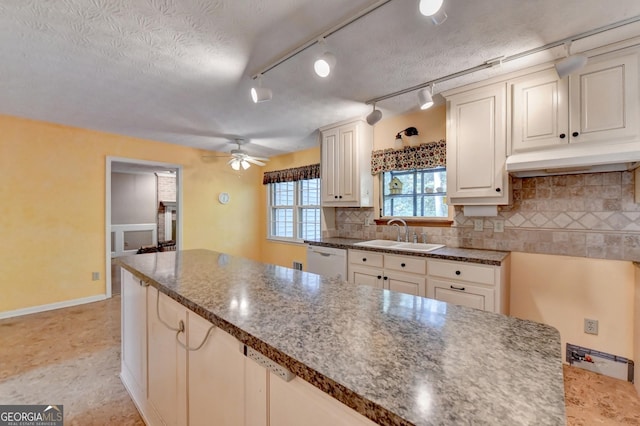 kitchen with tasteful backsplash, a textured ceiling, ceiling fan, sink, and dishwasher