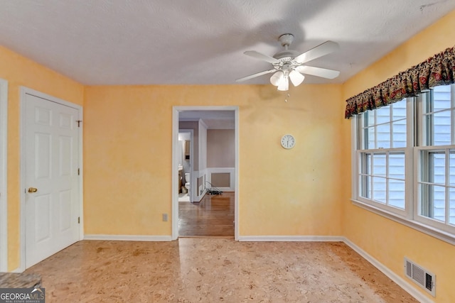 empty room with a textured ceiling and ceiling fan