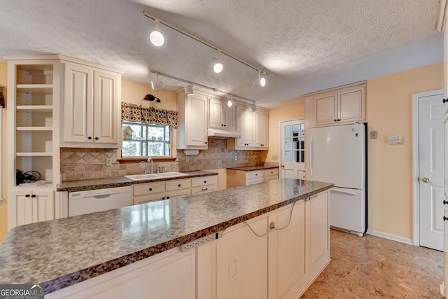 kitchen with a textured ceiling, white appliances, sink, and tasteful backsplash