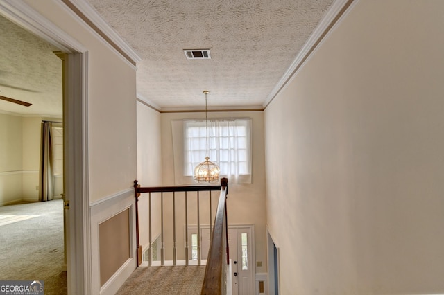 hall featuring carpet, crown molding, and an inviting chandelier