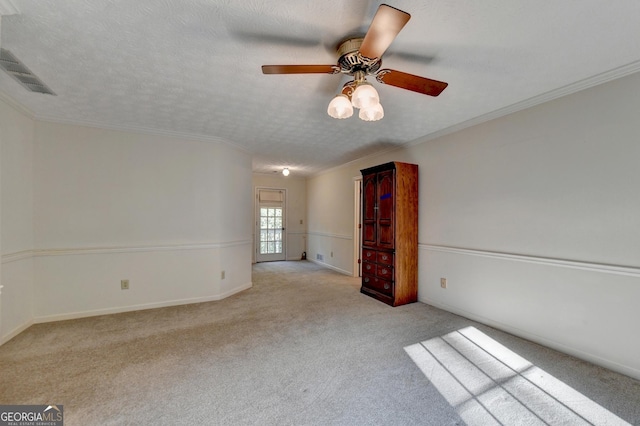 spare room with light carpet, a textured ceiling, ceiling fan, and ornamental molding