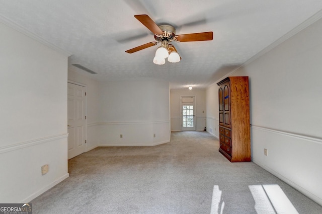 carpeted spare room with ceiling fan, crown molding, and a textured ceiling