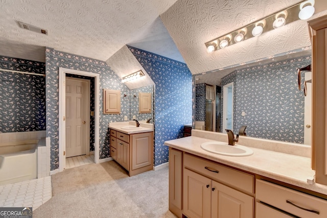 bathroom featuring lofted ceiling, a washtub, vanity, and a textured ceiling