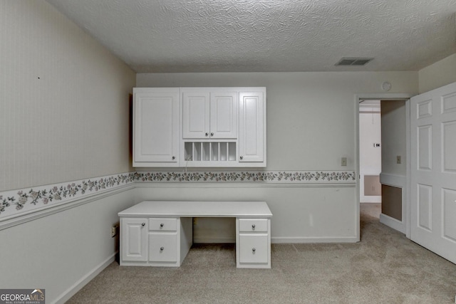 unfurnished office featuring a textured ceiling and light colored carpet