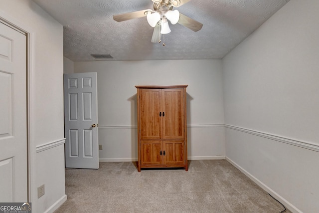 interior space with ceiling fan, light colored carpet, and a textured ceiling