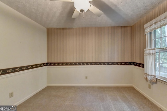 spare room featuring ceiling fan, light colored carpet, and a textured ceiling