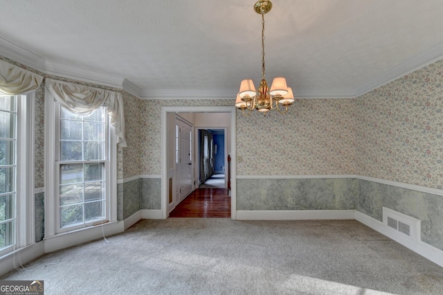 unfurnished dining area with carpet flooring, a notable chandelier, and crown molding